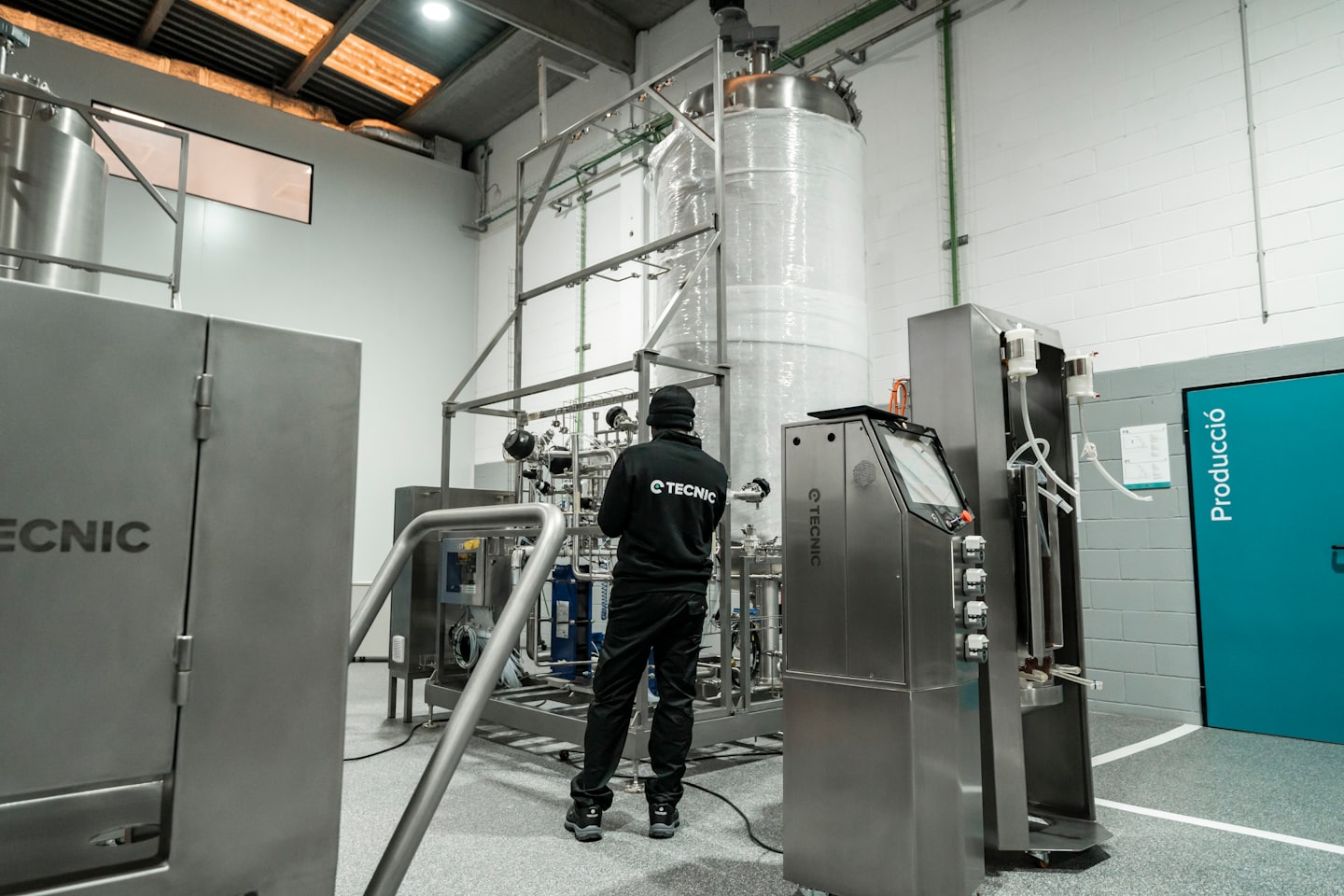 Technician inspecting complex stainless steel industrial machinery.