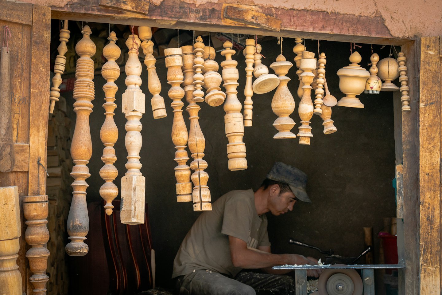 Craftsman shaping wood spindle on lathe in workshop.