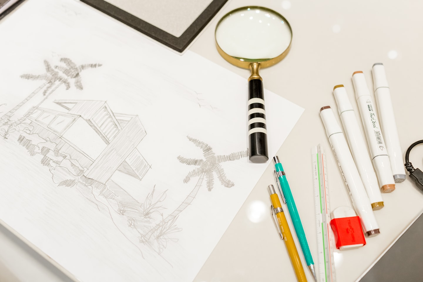 Architectural sketch of a modern house with palm trees and drafting tools.