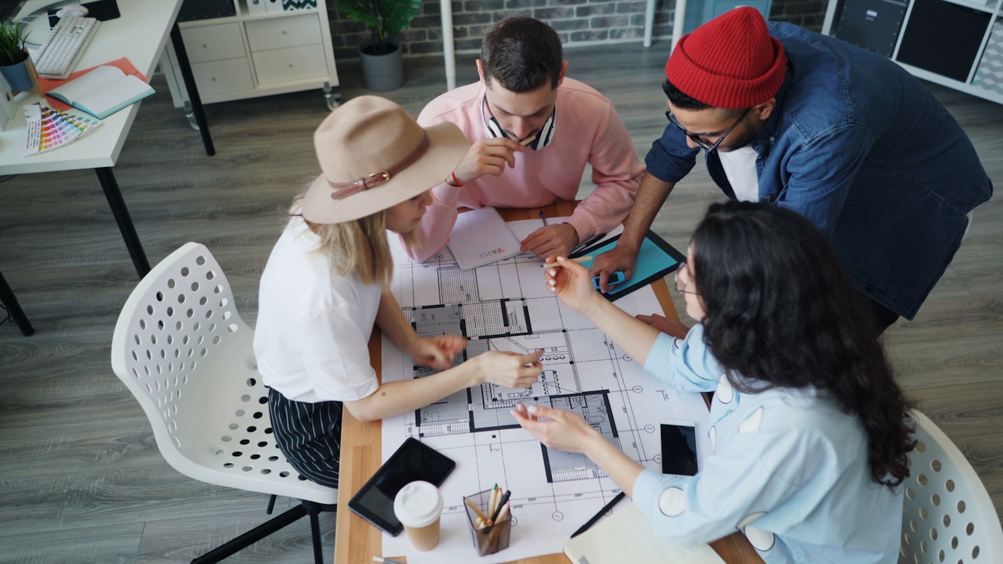 Diverse team collaborates on architectural blueprints in a modern office.
